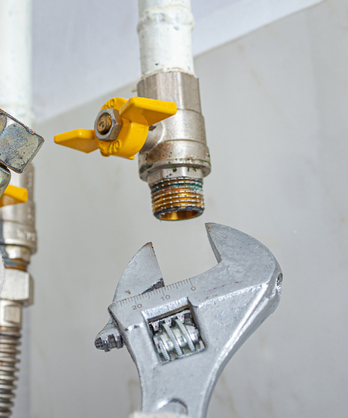 A couple of wrenches hanging from a pipe